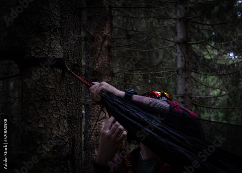 a man hanging up his hammock to take a break from hiking in the middle of a mountain forest photo