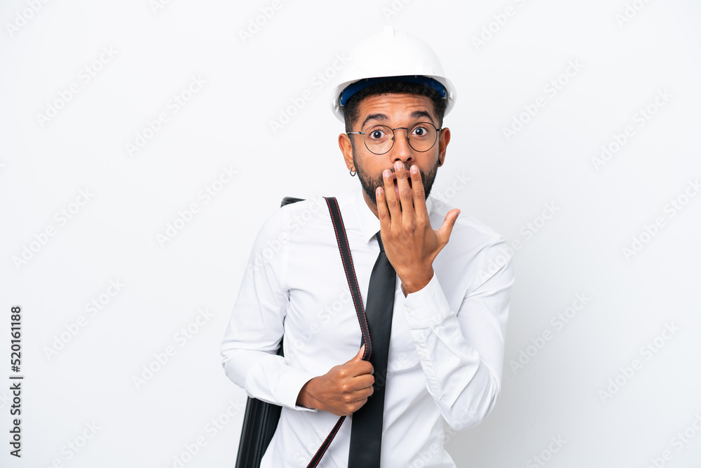 Young architect Brazilian man with helmet and holding blueprints isolated on white background happy and smiling covering mouth with hand Young architect Brazilian man with helmet and holding blueprints isolated on white background happy and smiling covering mouth with hand