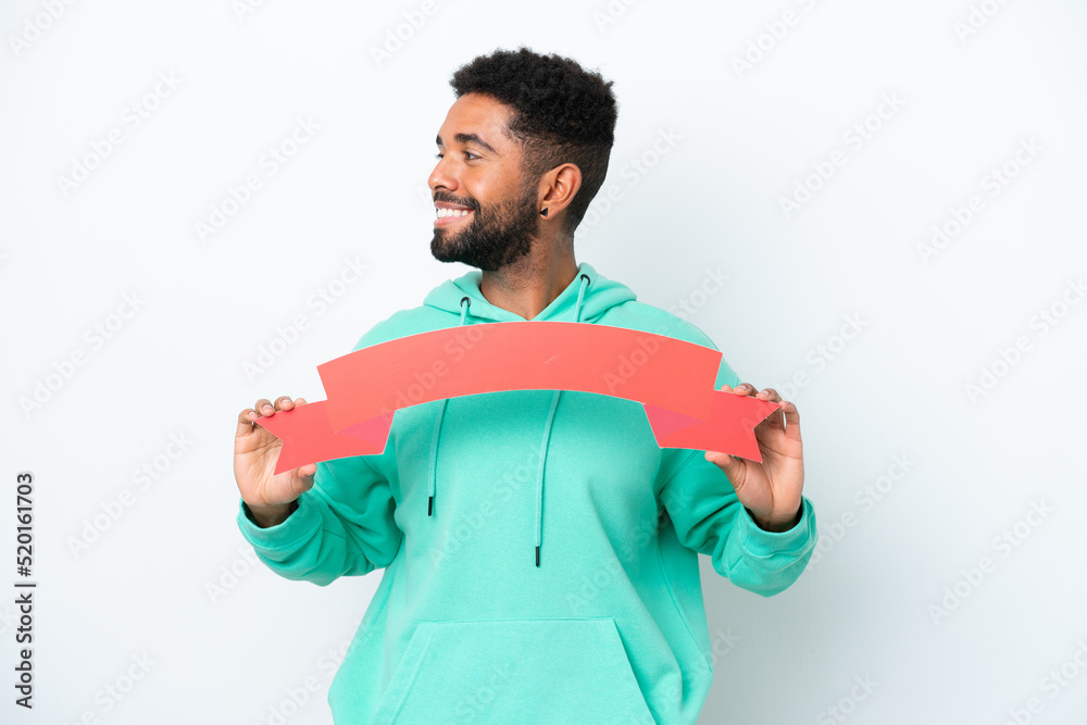 Young Brazilian man isolated on white background holding an empty placard and looking side Young Brazilian man isolated on white background holding an empty placard and looking side