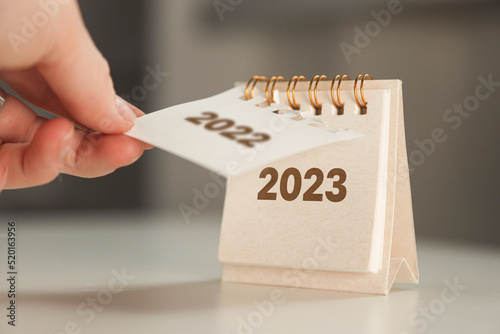 a woman's hand turns over a calendar sheet. year change from 2022 to 2023 © zatevakhin