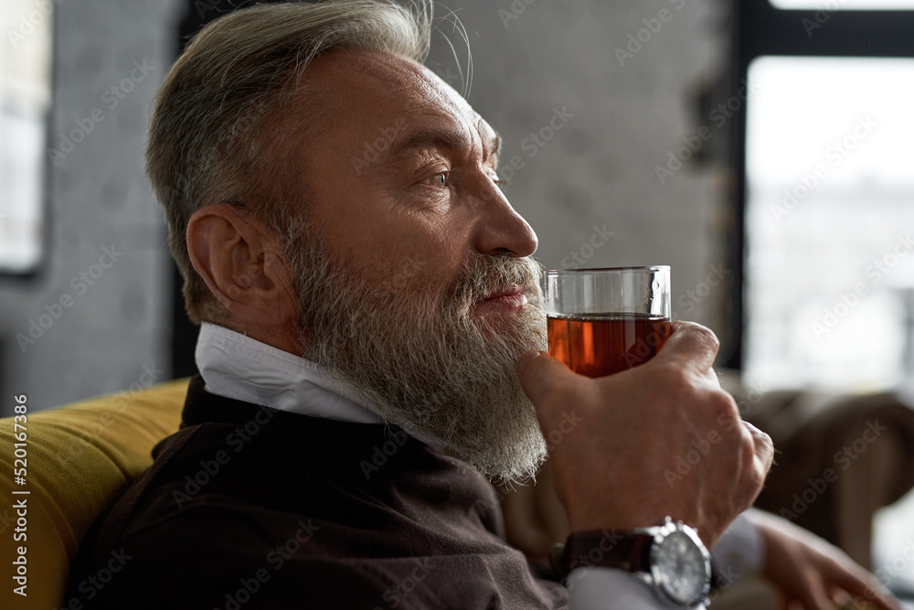 Elderly thoughtful man drinking cognac on sofa Elderly thoughtful man drinking cognac on sofa