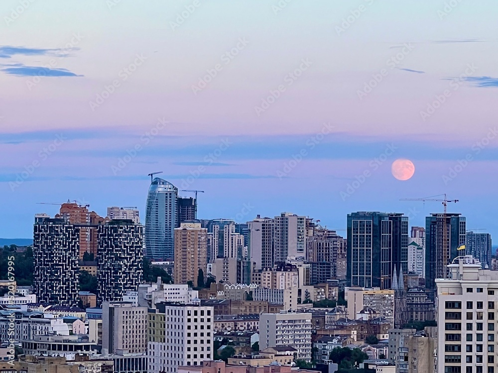 landscape of the evening city with a big moon in the sky
