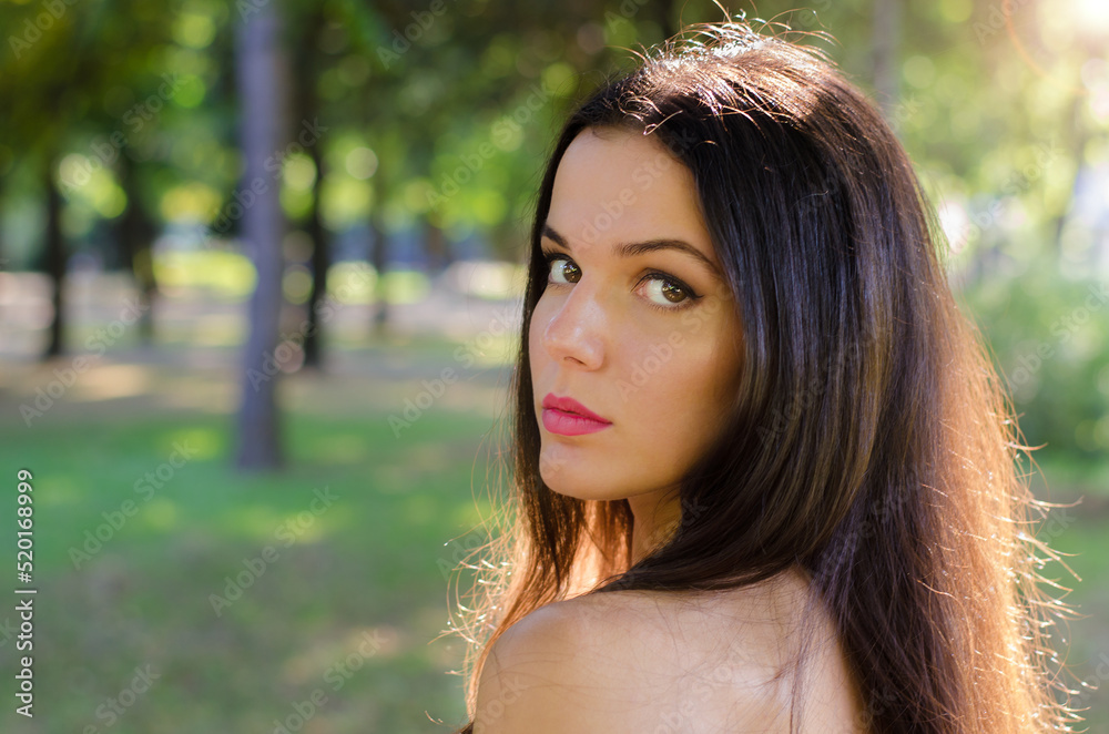 Naklejka premium Portrait of beautiful girl with long black hair in nature on sunny summer day