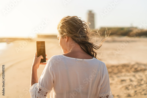 Φωτογραφία Chica joven en zona de playa junto a tienda de surf  al atardecer en la arena