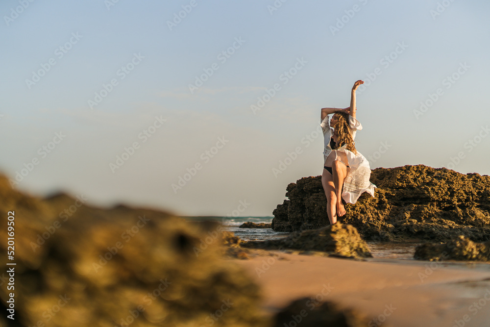 Chica Joven De Pelo Largo Sentada En Una Roca A La Orilla Del Mar Posando Y Mirando El Atardecer Chica Joven De Pelo Largo Sentada En Una Roca A La Orilla Del Mar Posando Y Mirando El Atardecer