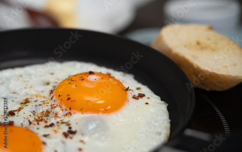 Fried eggs with spices and seasonings in hot frying pan. Breakfast