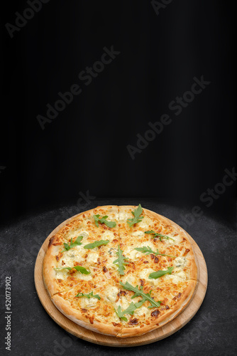 Four cheese pizza quattro fromaggi with arugula leaves on a wooden board on gray concrete. Top view Vertical banner