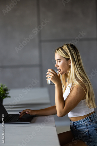 Wallpaper Mural Shot of beautiful woman working with laptop while drinking glass of water on desk in office at home. Refreshment, hydration and Healthy habit concept. Torontodigital.ca