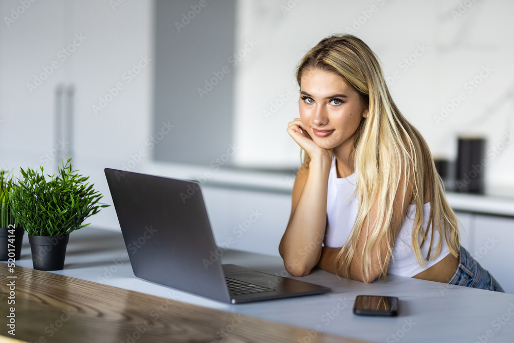 Fototapeta premium Happy young woman using laptop in cook room