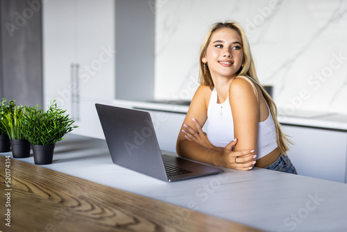 Cute smiling woman using laptop at home. Student girl working on computer. Online shopping, work from home, freelance, online learning, studying, lockdown concept. Distance education