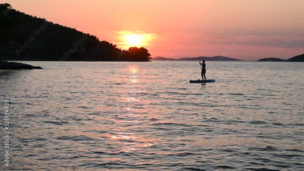 Silhouette of woman on stand up paddle board on the sea. Woman enjoying on Paddle-board at summer. SUP Silhouette of woman on stand up paddle board on the sea. Woman enjoying on Paddle-board at summer. SUP