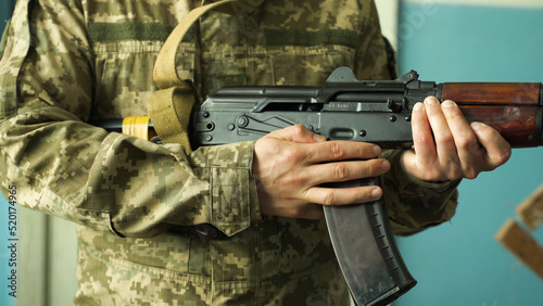 a soldier in camouflage uniform takes aim with his machine gun, preparing to fire close-up. fighting inside the building. firing at the enemy army. Kalashnikov shooting. combat clashes