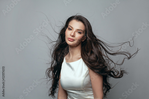 Glamorous young fashion model woman with long healthy windy hair in motion portrait