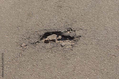 one small pit pothole with a crack on the gray asphalt road on the street