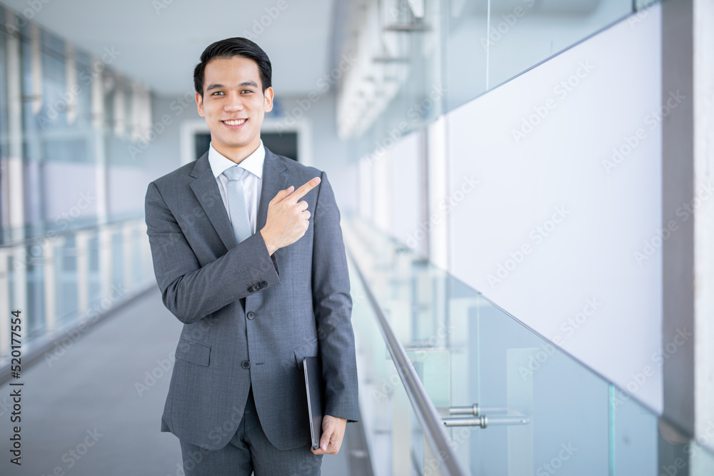 Young asian business man holding a tablet finger pointing away. Young asian business man holding a tablet finger pointing away.