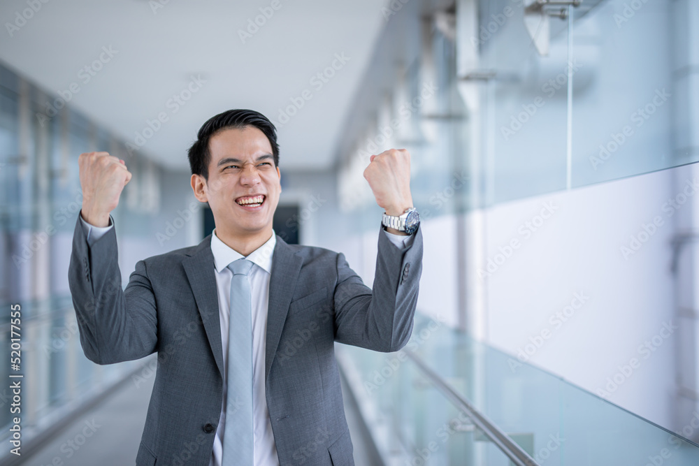 Asian businessman sucess raising fist and celebrating victory over office ,smart business concept. Asian businessman sucess raising fist and celebrating victory over office ,smart business concept.