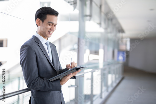 Young asian business man holding a tablet looking screen , smart business concept.