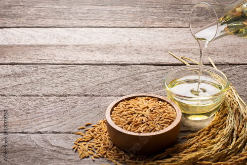 Rice bran oil with paddy rice on wooden table background.  photo