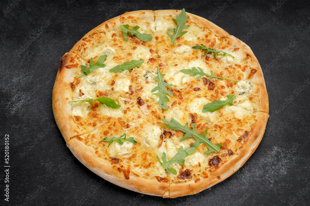 Four cheese pizza quattro fromaggi with arugula leaves on a wooden board on gray concrete horizontal
