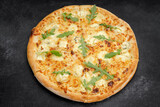 Four cheese pizza quattro fromaggi with arugula leaves on a wooden board on gray concrete horizontal