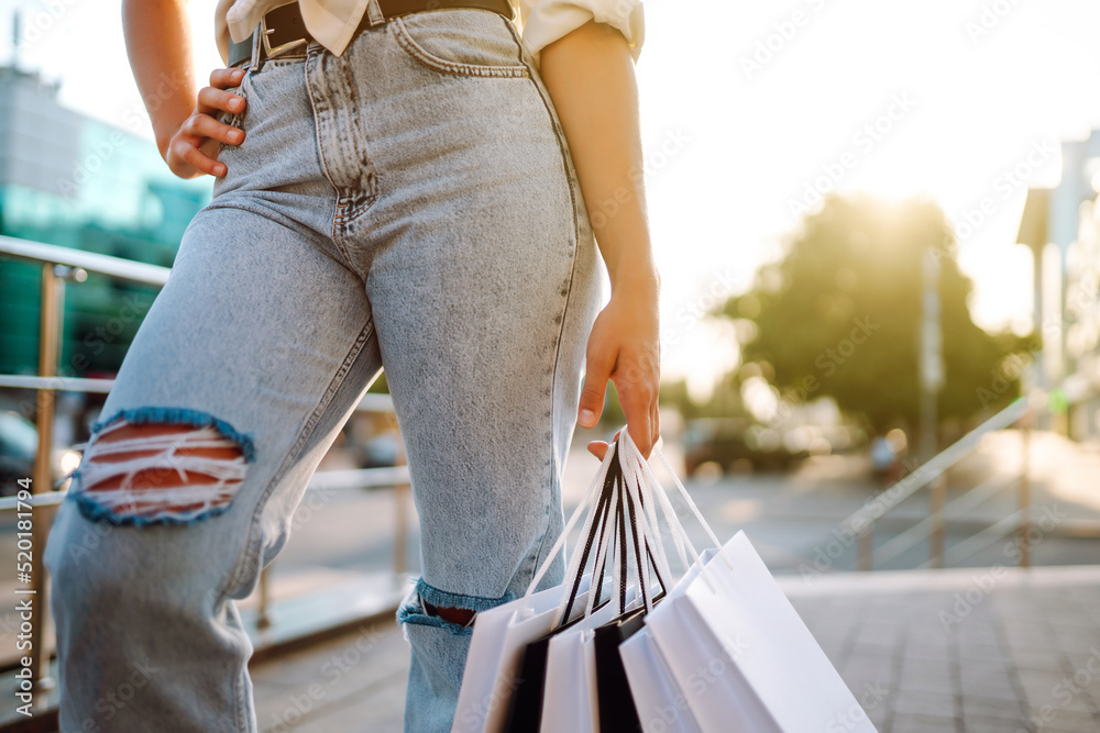 Young woman with shopping bags walking on street.  Consumerism, sale, purchases, shopping, lifestyle concept.