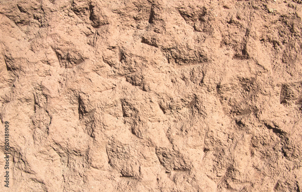 Background - an orange-red wall with dents and bumps.