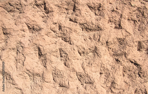 Background - an orange-red wall with dents and bumps.