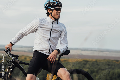 Fototapeta Naklejka Na Ścianę i Meble -  Professional Male Cyclist with His Bike Outdoors, Adult Man Wearing Helmet and Protection Sport Glasses Looking Away, Copy Space