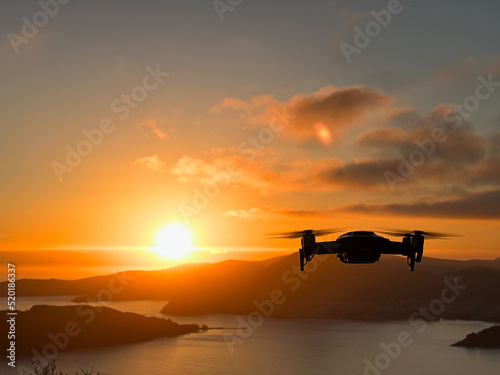 Drone hovers over the sea against the backdrop of mountains at sunset © Nadtochiy