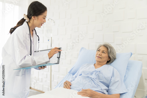 Nurse, elderly patient and hospital. Nurse discussing and writing note to seek advice with elderly asian woman on bed at the hospital. People and health care concept