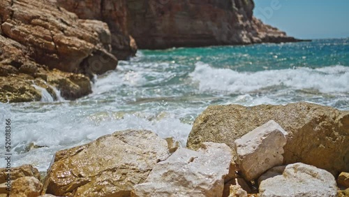 slow motion sea waves crashing and foaming against rocky pebble beach on mediterranean sea shore. golden rocks coast meeting deep blue ocean water. Summer Tourism in Turkey concept photo