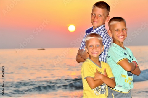 three happy brothers enjoy the sunset on the beach on a sunny summer day