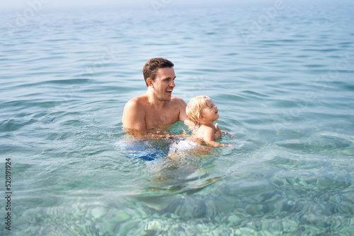 Dad teaches little girl to swim in the sea © Nadtochiy