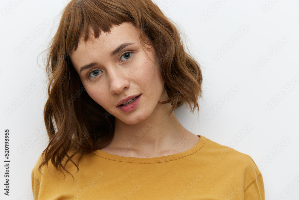 a beautiful, sweet, relaxed woman stands on a light background in a yellow T-shirt and looks at the camera with a pleasant smile. Horizontal photo with empty space a beautiful, sweet, relaxed woman stands on a light background in a yellow T-shirt and looks at the camera with a pleasant smile. Horizontal photo with empty space
