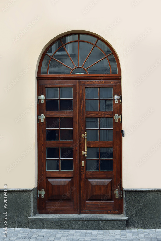 Obraz premium Entrance of house with beautiful arched wooden door and transom window