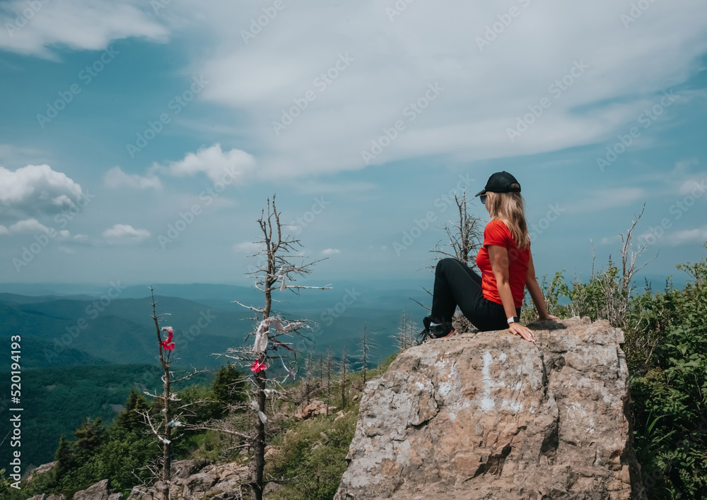 A girl on top of Falaza mountain looks at a beautiful mountain valley. Travel and tourism. Hiking High quality photo