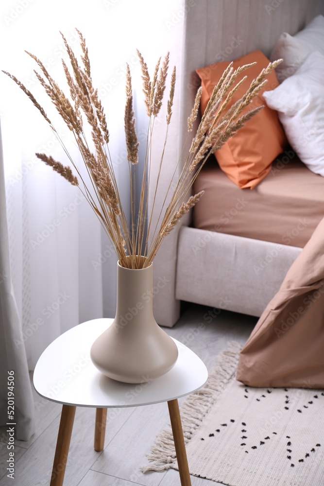 Vase with decorative dried plants on table in bedroom. Interior design Vase with decorative dried plants on table in bedroom. Interior design