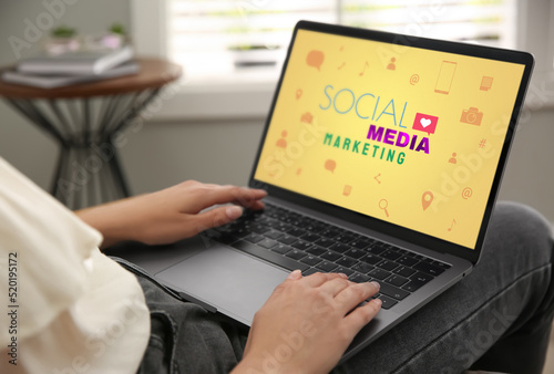SMM (Social Media Marketing) concept. Woman working with modern laptop indoors, closeup