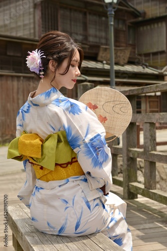 うちわ片手に小江戸佐原の町並みでポーズをとる浴衣を着た若い女性