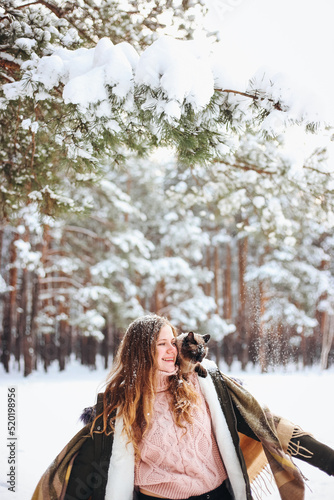 Girl woman and cat sitting on her shoulder in snowy winter forest