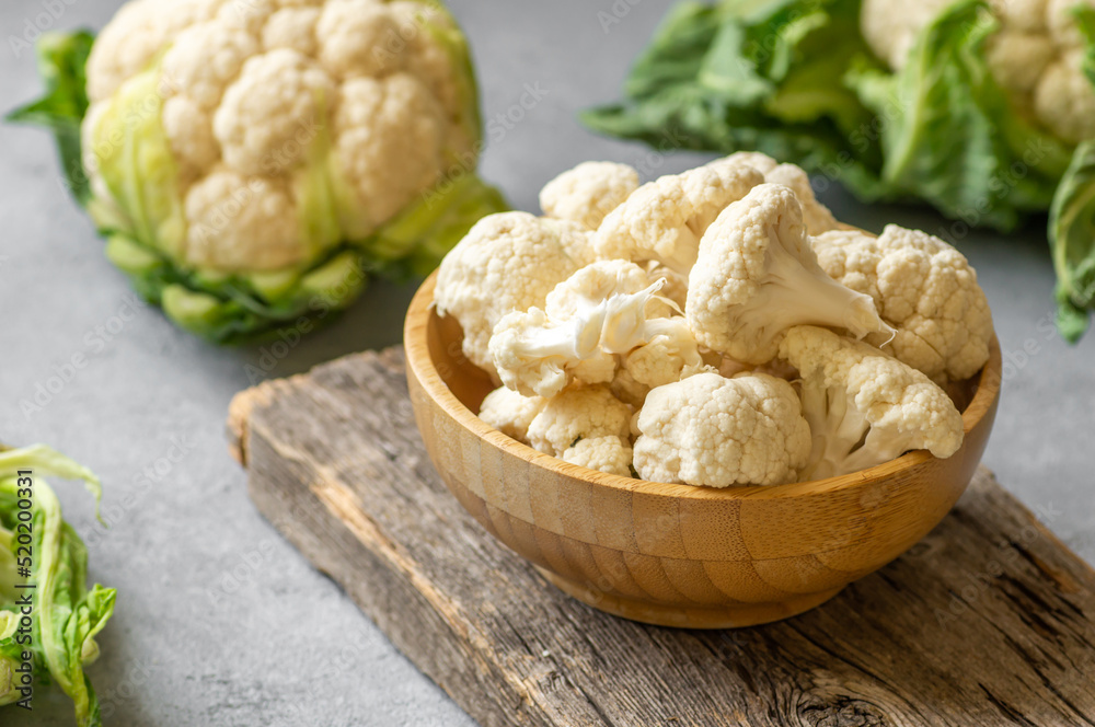 Fresh raw organic cauliflower with leaves on rustic background, uncooked vegetable Fresh raw organic cauliflower with leaves on rustic background, uncooked vegetable