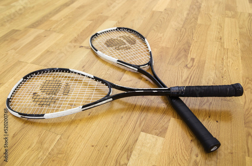Two old squash rackets lie on a parquet background © ribalka yuli
