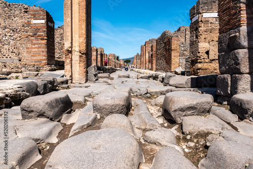 Fototapeta Naklejka Na Ścianę i Meble -  POMPEII, ITALY - MAY 04, 2022 - A crosswalk of a typical Roman road in the ancient city of Pompeii, Italy