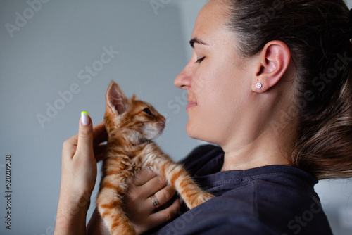 Young woman playing with little ginger cat at home