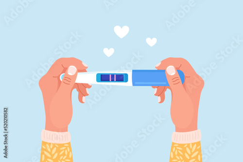 Beautiful female hand is holding a pregnancy or ovulation test with positive result as a two lines. Pregnant woman waiting childbirth. Planning a baby, motherhood and healthcare concept