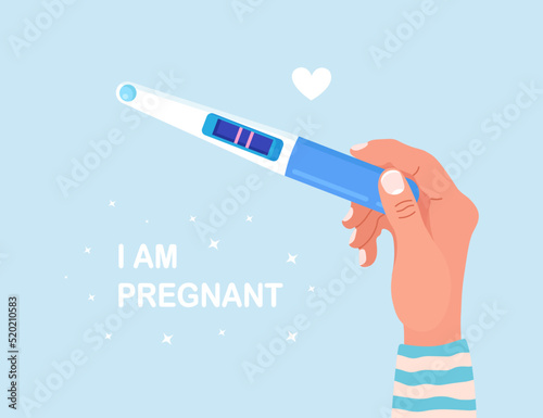 Beautiful female hand is holding a pregnancy or ovulation test with positive result as a two lines. Pregnant woman waiting childbirth. Planning a baby, motherhood and healthcare concept