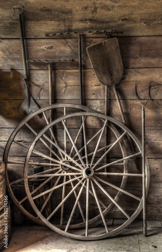 old wooden cart wheels with farm tools in a barn