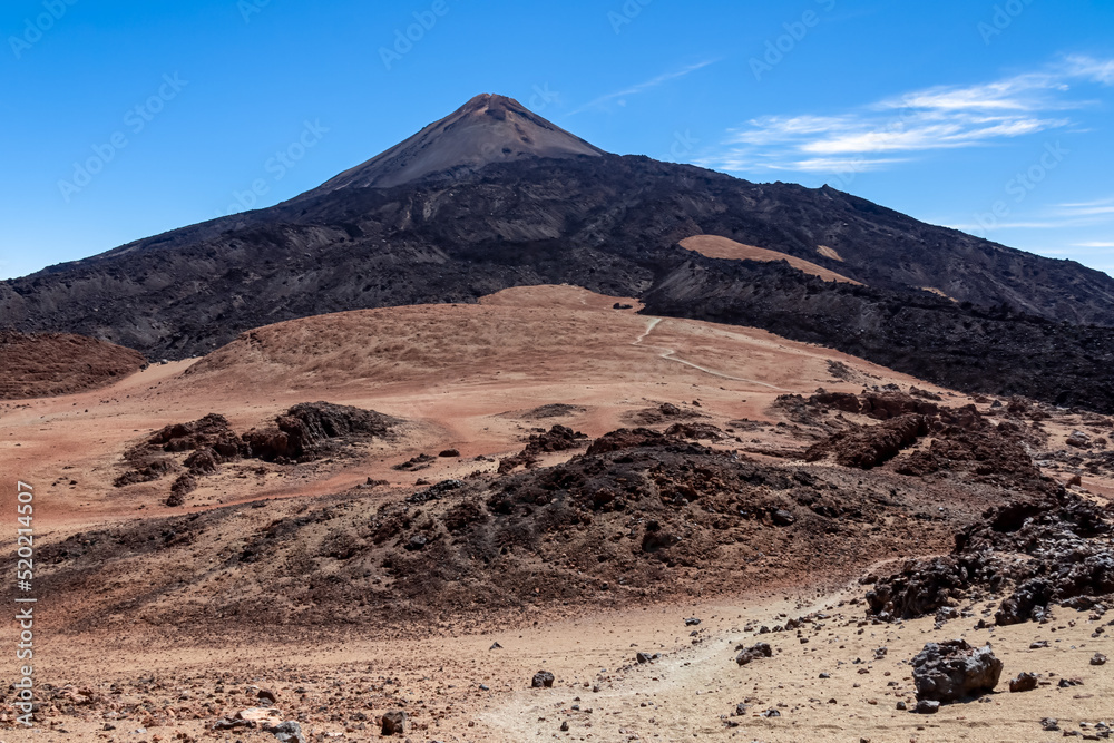 Hiking trail over volcanic desert terrain leading to summit of volcano Pico del Teide from Pico Viejo, Mount Teide National Park, Tenerife, Canary Islands, Spain, Europe. Solidified lava, ash, pumice
