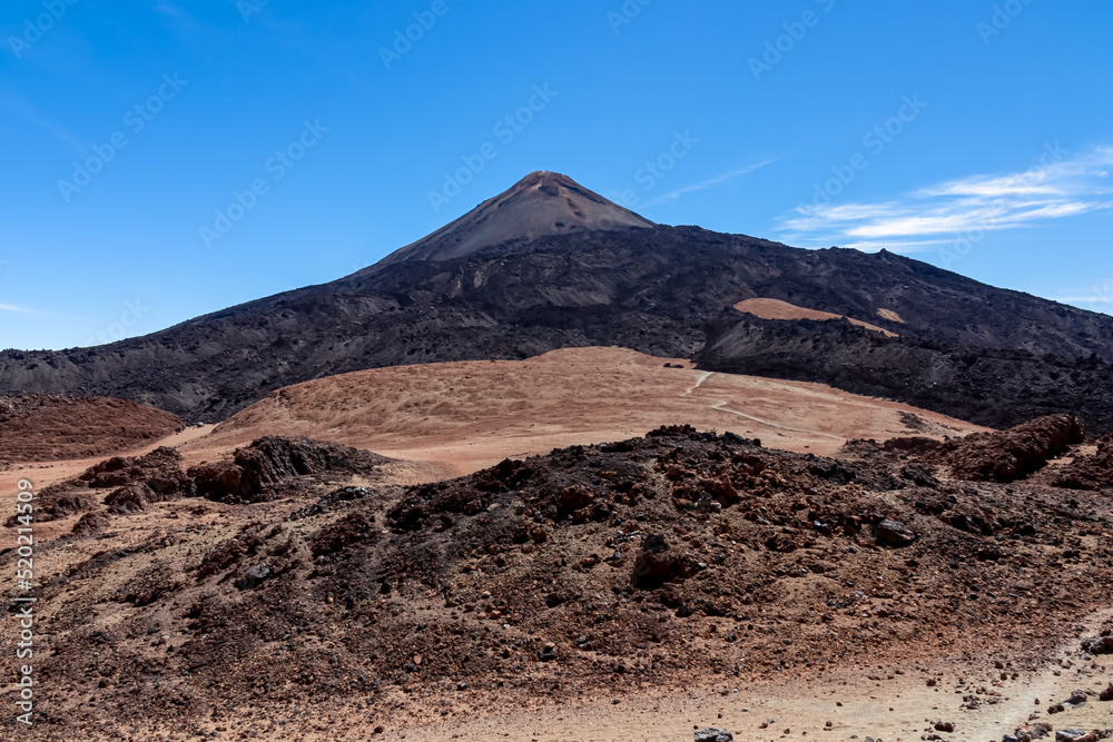 Hiking trail over volcanic desert terrain leading to summit of volcano Pico del Teide from Pico Viejo, Mount Teide National Park, Tenerife, Canary Islands, Spain, Europe. Solidified lava, ash, pumice Hiking trail over volcanic desert terrain leading to summit of volcano Pico del Teide from Pico Viejo, Mount Teide National Park, Tenerife, Canary Islands, Spain, Europe. Solidified lava, ash, pumice