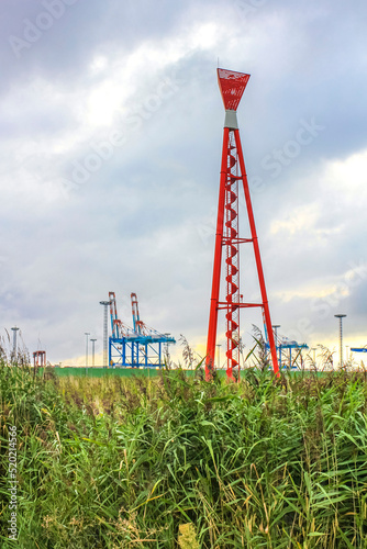 Industrial area cranes red tower lighthouse dyke seascape panorama Germany. photo